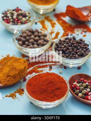 Aromatische Gewürze und Gewürze. Helle Farben indischer Gewürze. Orange Paprika in der Schüssel auf hellblauem Hintergrund. Konsistenz von Würzmitteln Nahaufnahme. Stockfoto
