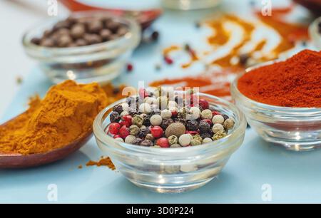 Aromatische Gewürze und Gewürze. Helle Farben indischer Gewürze. Farbige Paprika in der Schüssel auf hellblauem Hintergrund. Konsistenz von Würzmitteln Nahaufnahme. Stockfoto