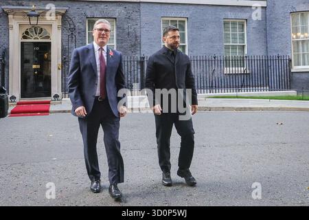 London, Großbritannien. Oktober 2025. Wolodymyr Zelenskyy, Präsident der Ukraine, und Sir Keir Starmer, Premierminister des Vereinigten Königreichs, gehen von der Downing Street 10 zum Außenministerium, wo sie von ukrainischen Kindern mit Fahnen begrüßt werden. Starmer wird Zelenskyy und andere führende Politiker zu den Treffen der "Koalition der Willigen" im Auswärtigen Amt begrüßen. Quelle: Imageplotter/Alamy Live News Stockfoto