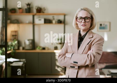 Porträt einer selbstbewussten Frau mittleren Alters, die mit überkreuzten Armen steht Stockfoto