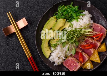 Gebratene Thunfisch-Tataki in einer Schüssel mit Sesamsamen, Reis und Gemüse. Thunfisch Tataki als Hintergrund für Ihr Design. Stockfoto