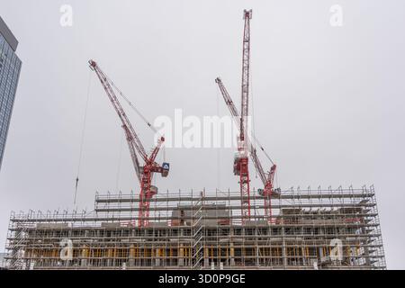 Deutschland Berlin 7. Oktober 2025. Kräne und Baustelle. Zwei große rote Kräne überragen eine Baustelle in Berlin. Gerüst bedeckt die r Stockfoto