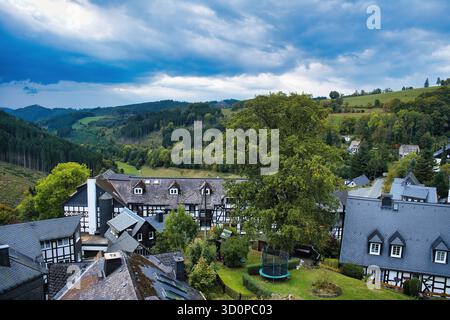 Fachwerkhäuser mit Schieferdächern in einem bewaldeten Tal im Sauerland. Holthausen, Gemeinde Schmallenberg, Nordrhein-Westfalen Stockfoto