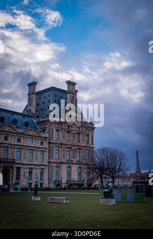 Ein Park mit einer weißen Marmorstatue im Vordergrund, umgeben von blattlosen Bäumen und Bänken, mit klassischen Gebäuden im Hintergrund. Stockfoto