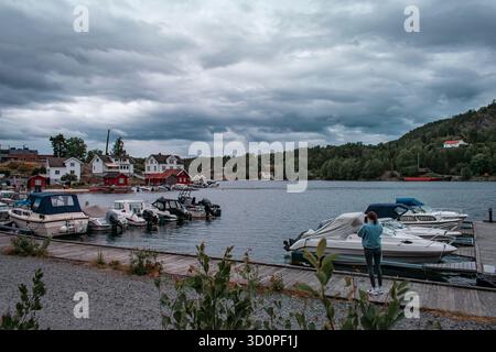 Eine malerische Hafenszene mit mehreren kleinen Booten, die entlang einer Uferpromenade mit farbenfrohen Häusern und Gebäuden angedockt sind. Stockfoto