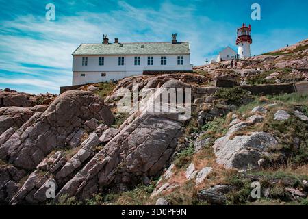 Ein malerischer Leuchtturm an einer felsigen Küste mit einem kleinen weißen Gebäude. Stockfoto