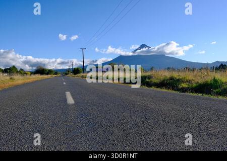 Malerische Ausblicke auf Mount Taranaki (Mount Egmont) in der Nähe von New Plymouth, Neuseeland, mit ländlichen Landschaften, Straßen und üppigem Grün unter blauem Himmel. Stockfoto