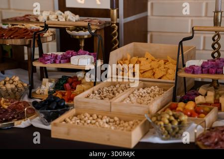 Ein einladender Overhead Shoot zeigt eine üppige Wurstplatte mit verschiedenen Käsesorten, Wurstwaren, bunten Oliven, gemischten Nüssen und c Stockfoto