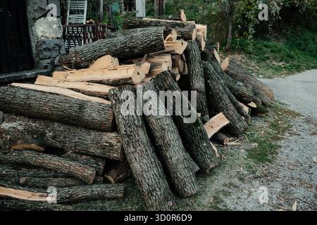 Stapel geschnittener Holzscheite, die in der Nähe des Hauses im serbischen Dorf gestapelt sind und einen nachhaltigen ländlichen Lebensstil darstellen. Die Dorfbewohner haben Brennholz für den Winter vorbereitet Stockfoto