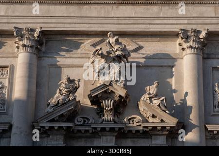 Kirche San Stae - Saint Eustace (Sant'Eustacchio, Eustachio) in Venedig, Italien. Skulpturen am Giebel der spätbarocken Fassade. Zwei Engel von Giusepp Stockfoto