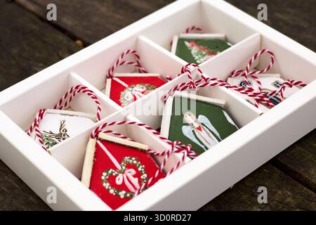 Handgefertigte Weihnachtsschmuck in einer weißen Box mit roter und weißer Schnur, einschließlich Engel, Haus, Baum, Hirsch, und Weihnachtskranzmotive. Stockfoto
