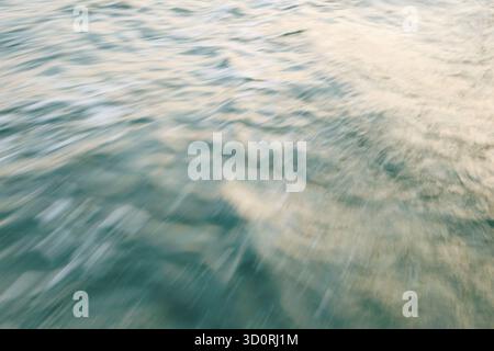 Abstrakte Bewegungsunschärfe sanfter Ozeanwellen mit sanfter Sonnenlichtreflexion. Stockfoto