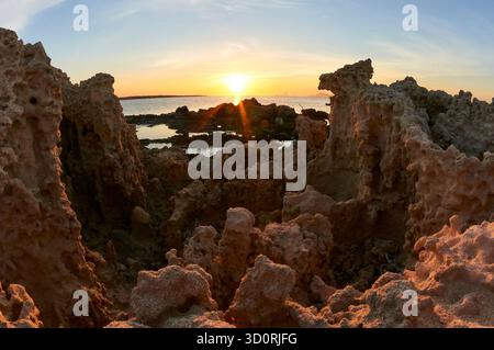 Sonnenuntergang von der Sandsteinküste von SES Bassetes, mit der Insel es Vedrà am anderen Ende (Naturpark SES Salines, Formentera, Mittelmeer, Spanien) Stockfoto