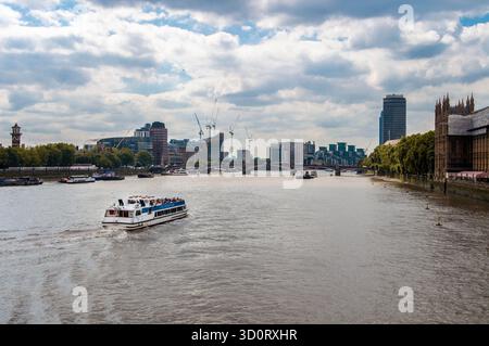 Touristenboot, das entlang der Themse in London mit Blick auf die Skyline der Stadt und Brücken fährt. Stockfoto