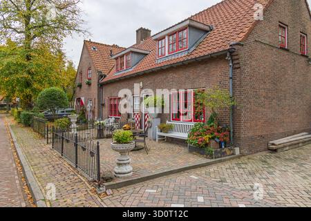 Malerische Straßenszene in Haarzuilens mit traditionellen Backsteinhäusern mit charakteristischen roten Fensterrahmen und einem bezaubernden Vorgarten. Stockfoto
