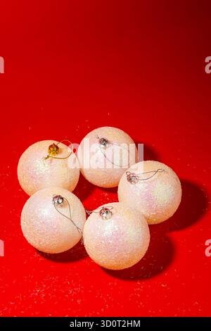 Minimalistische festliche Komposition mit eleganten weißen Weihnachtskugeln auf einer hellroten Oberfläche Stockfoto