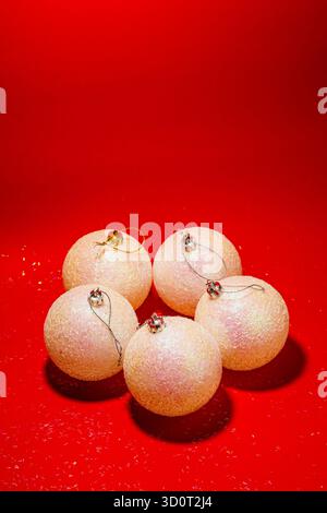 Minimalistische festliche Komposition mit eleganten weißen Weihnachtskugeln auf einer hellroten Oberfläche Stockfoto