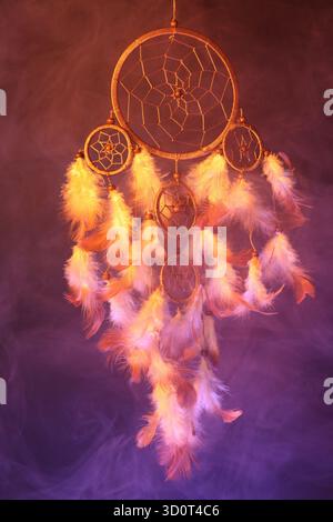 Schöner Traumfänger und Rauch in Farbe hell auf dunklem Hintergrund Stockfoto