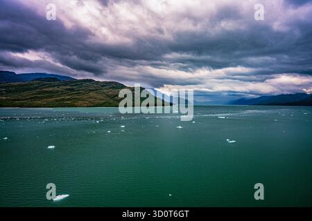 Der riesige See reflektiert den stimmungsvollen Himmel und die ferne Bergkette und schafft eine atemberaubende Naturkulisse Stockfoto