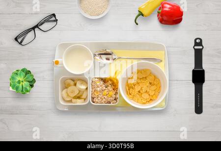 Gesundes Frühstück mit Banane, Müsli, Mandelmilch und Smartwatch auf Holztisch, symbolisiert Fitness, Wellness und achtsamen Morgen Stockfoto