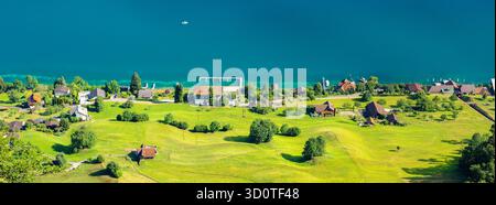 Panoramablick vom Burgenstock auf eine malerische Uferlandschaft mit grünen Hügeln, einem ruhigen Vierwaldstättersee und kleinen Häusern Stockfoto