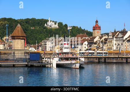 Luzern, Schweiz - 11. Juli 2025: Malerischer Blick auf Luzern mit Kapellbrücke, Wasserturm und Dampfschiff auf dem Vierwaldstättersee. Stockfoto