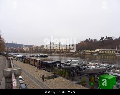 Prag, Tschechische Republik - 13. Dezember 2024: Blick auf die Prager Uferpromenade mit festgefahrenen Booten, Fußweg am Fluss Vitava Stockfoto
