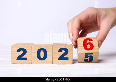 Neujahr. Frau, die den Würfel mit den Zahlen 5 und 6 umdreht, um 2026 auf weißem Hintergrund zu machen, Nahaufnahme Stockfoto