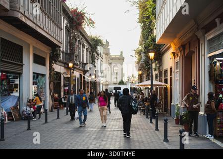 Straßenszene bei Sonnenuntergang im historischen Zentrum von Lima, Peru, 2024. Fußgänger laufen entlang einer Kolonialstraße, die von Cafés und alten Gebäuden gesäumt ist. Stockfoto