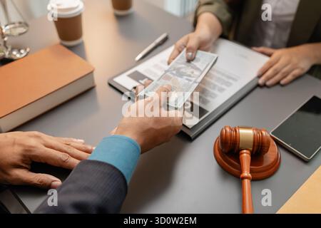 Ein Kunde übergibt Geld an einen Anwalt, der an einem Schreibtisch sitzt, was eine Zahlung für Rechtsdienstleistungen, eine Vertragsvereinbarung oder einen Abrechnungsprozess in einem prof Stockfoto