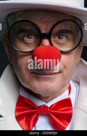 Nahporträt eines Clown. Ein älterer Mann mit weißem Mantel und Hut. Stockfoto