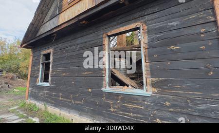 Verkohltes Holzhaus mit kaputten Fenstern, die Zerstörung nach dem Feuer zeigen Stockfoto
