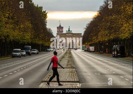 Berlin, Deutschland. Oktober 2025. Ein Jogger blickt bei Sonnenaufgang auf das Brandenburger Tor. Quelle: Christophe Gateau/dpa/Alamy Live News Stockfoto