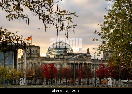 Berlin, Deutschland. Oktober 2025. Vor dem Reichstagsgebäude stehen Bäume mit roten und gelben Blättern im Herbst. Quelle: Christophe Gateau/dpa/Alamy Live News Stockfoto
