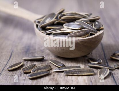 Gestreifte Sonnenblumenkerne in einem Löffel auf einem Holztisch. Nahansicht. Stockfoto