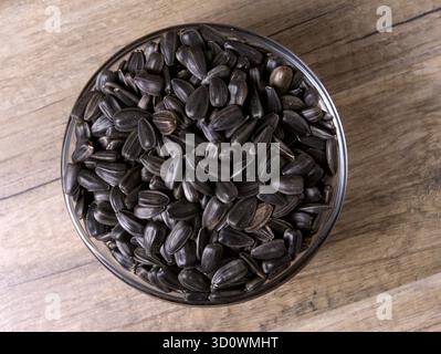 Schwarze Sonnenblumenkerne in einer Glasschale auf einem Holztisch. Nahansicht. Stockfoto