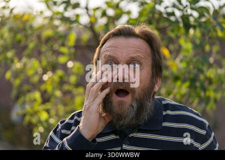 Porträt eines verängstigten Mannes, Nahaufnahme. Ältere bärtige kaukasische Männer in der Natur. Gesichtsbärtige kaukasische männliche in einer Notsituation gefangen Stockfoto