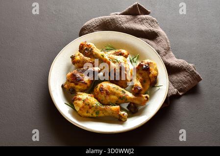 Knusprig gebackene Hähnchenkeulen auf Teller auf braunem Hintergrund. Nahansicht Stockfoto