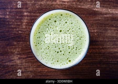Glas grüner Smoothie, Nahaufnahme, Draufsicht. Gesundes Bio-Getränk aus Banane, Dill, Petersilie und Avocado. Blasen und Schaum auf der Oberfläche eines g Stockfoto