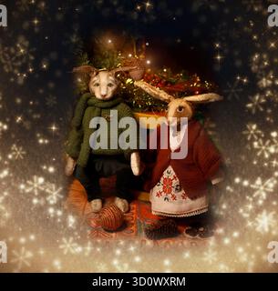 Vintage-Weihnachtskarte. Ein Paar Marionettenkaninchen sitzt unter einem Weihnachtsbaum. Retro-STYLE. Weihnachtsgrüße. Stockfoto