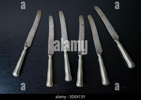 Rostiges Silbergeschirr Messer und Gabel auf schwarzen Möbeln Stockfoto