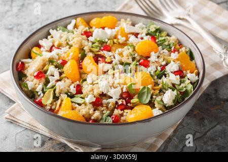 Granatapfel und Orangen Quinoa Salat mit Spinat, Feta und knusprigen Pistazien auf dem Teller auf dem Tisch. Horizontal Stockfoto
