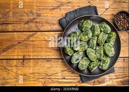 Rohe, nahrhafte gefrorene Spinatblöcke auf einem dunklen Teller, bereit zum Auftauen und Kochen. Traditionelle rustikale Lebensmittelfotografie Stockfoto