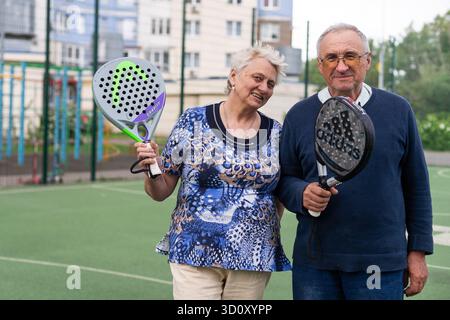 Ukraine, Kiew, 05. Mai 2024, glückliche fröhliche positiv lächelnde Padel-Spieler verschiedener Generationen posieren auf dem Padel-Hof Stockfoto