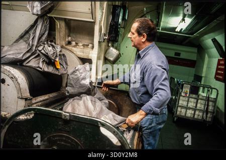 Postarbeiter, der Postsäcke auf ein Förderband lädt. Mount Pleasant Underground Mail Train, London, Großbritannien. 1990er Jahre Stockfoto