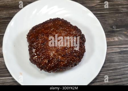 Gekochtes Hamburger-Patty aus gemahlenem Rindfleisch, eine Hackfleischscheibe, typischerweise gewürzt, aus gemahlenem Rindfleisch gebildet, in flachem Öl gegrillt, gekochtes Fleisch Stockfoto