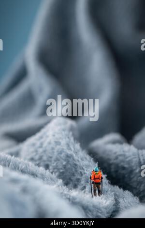 Eine Bergsteiger Figur auf flauschigem Fleece-Material, das wie eine schneebedeckte Bergoberfläche aussieht Stockfoto