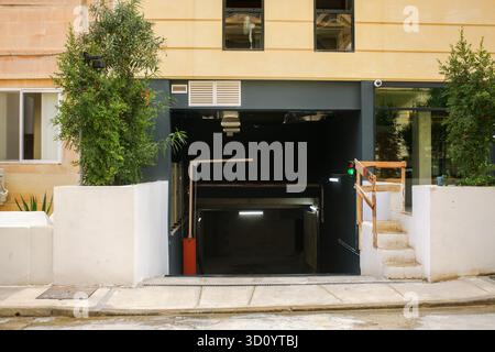 Moderne Tiefgarage mit erhöhter Absperrung, grüner Ampel und mediterranen Pflanzen an einer Stadtstraße. Stockfoto