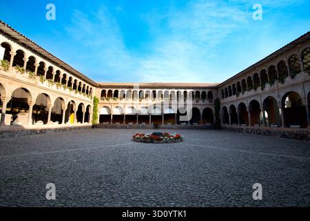 Historischer Innenhof des Klosters von Santo Domingo (Qorikancha) in Cusco, Peru, mit Kolonialbögen, Inka-Mauerwerk und einem hellblauen Himmel. Stockfoto