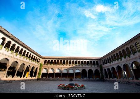 Historischer Innenhof des Klosters von Santo Domingo (Qorikancha) in Cusco, Peru, mit Kolonialbögen, Inka-Mauerwerk und einem hellblauen Himmel. Stockfoto